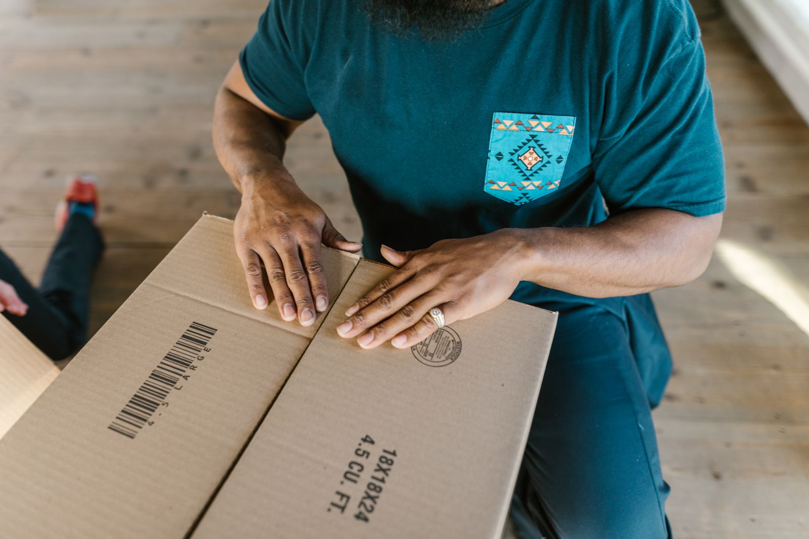 Hands checking a cardboard package with a printed barcode.