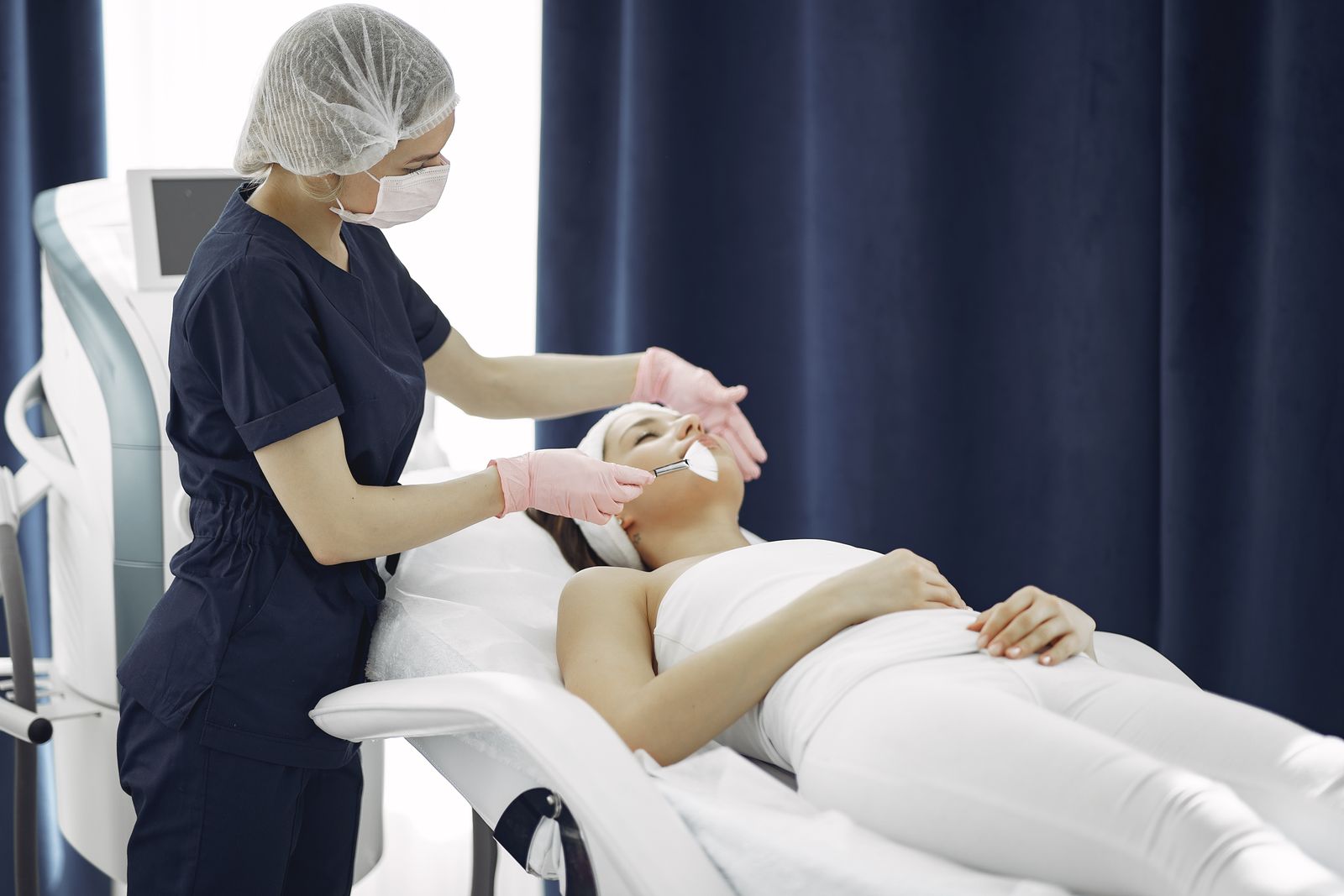 A skincare professional applying a facial product with a brush